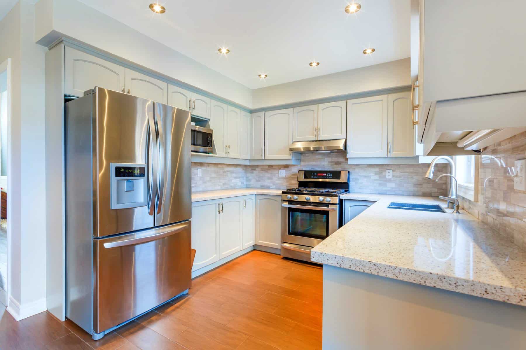 Cabinet Refinishing Kitchen Cream-painted kitchen cabinetry with blue-gray trim, stainless steel appliances, and granite countertops