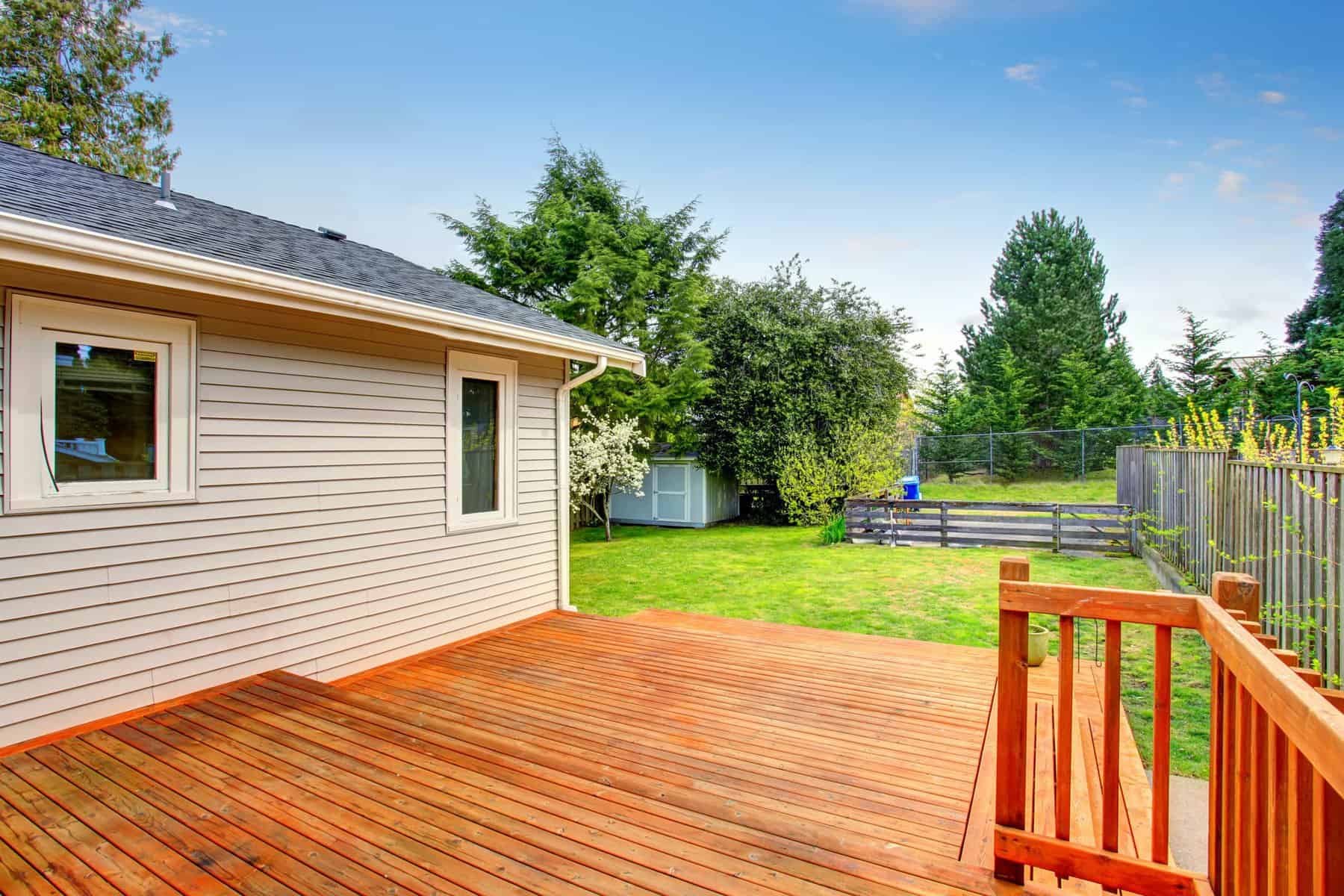 Exterior Deck Painting Rich honey-orange stained wooden deck with matching railing adjoining cream horizontal vinyl-sided home in Raleigh, NC