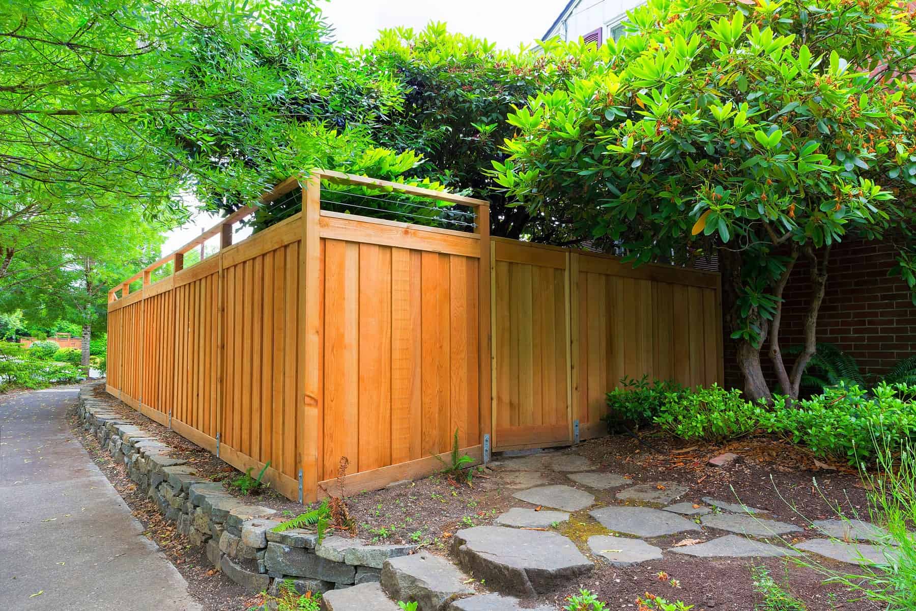 Orange Stained Wood Fence Orange-stained wood fence with vertical board siding and green lattice top in residential setting