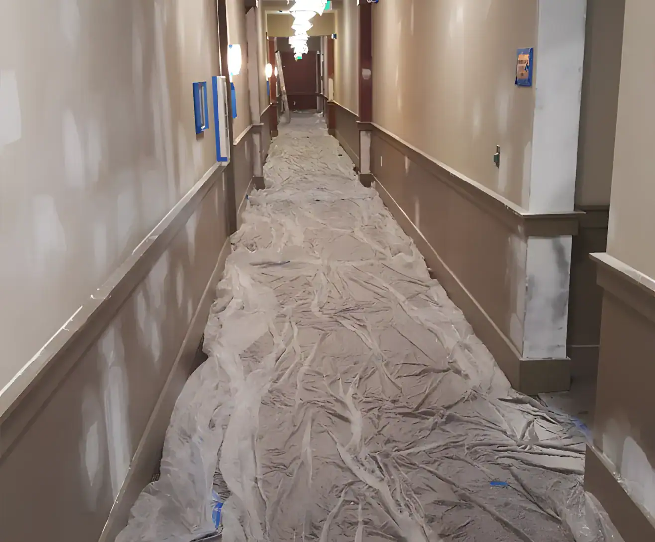 Commercial Hallway Interior Painting Tan-painted commercial hallway with protective floor coverings, white upper walls, and wooden handrails