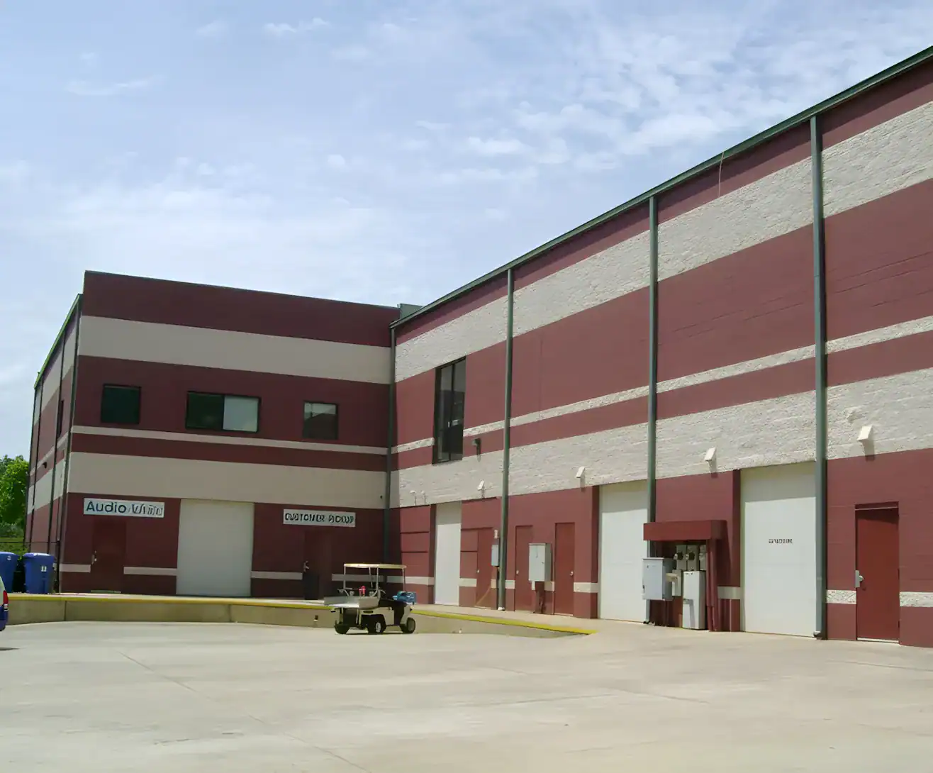 Burgundy And Cream Striped Commercial Building Burgundy and cream horizontal-striped commercial building exterior with metal roof trim and large garage doors