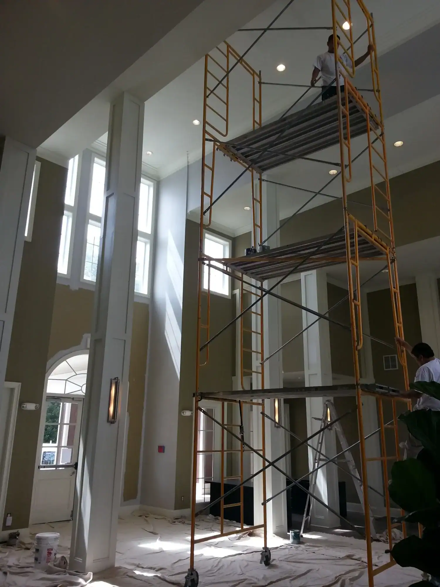 Interior Residential Painting Raleigh Tall interior foyer with freshly painted white walls, recessed lighting, and tall scaffolding during residential painting