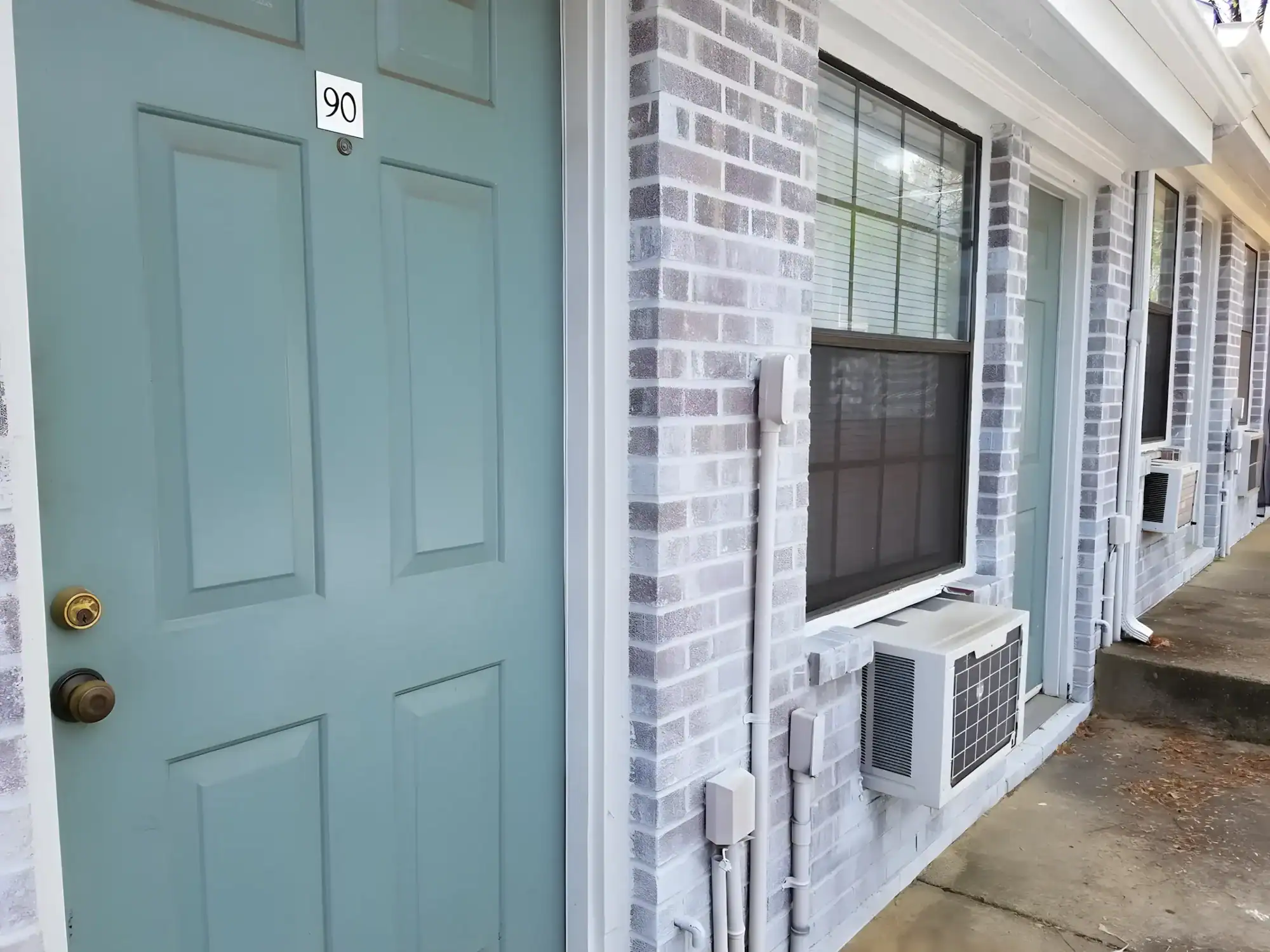 Seafoam Green Residential Entry Door Seafoam green painted six-panel residential entry door with brass hardware on brick building exterior