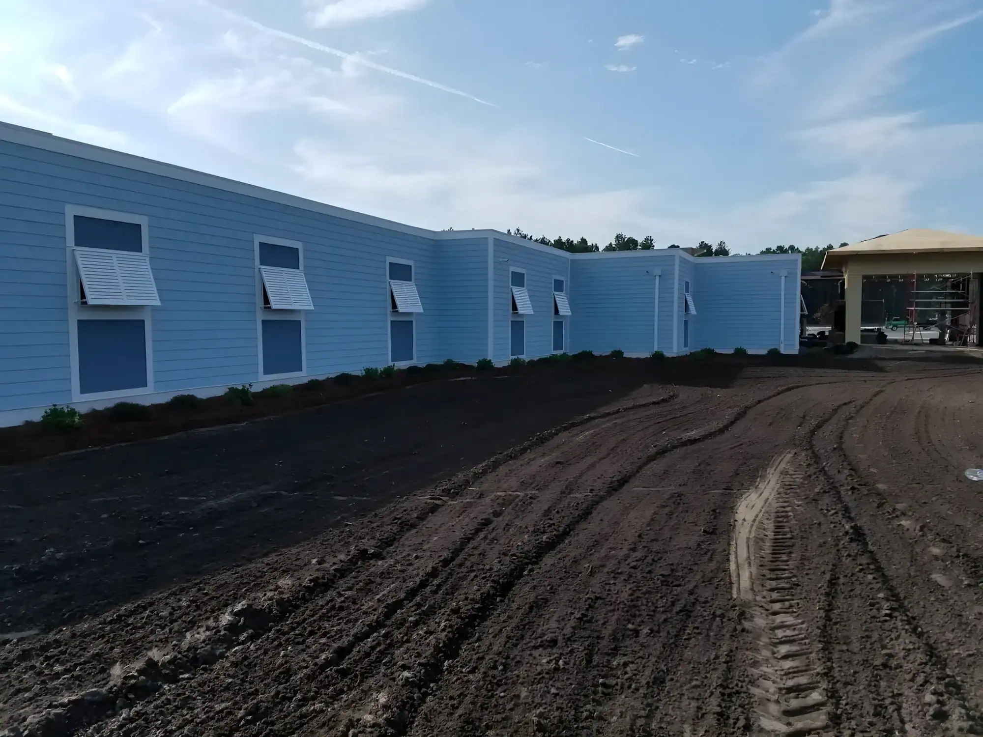Bright Blue Residential Building Exterior Bright blue-painted residential building exterior with white-trimmed windows and dark landscaping