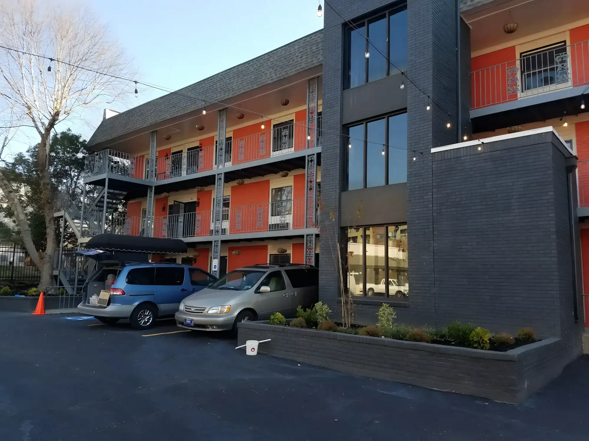 Modern Multi Unit Residential Exterior Modern residential multi-unit building with orange-painted facade, dark gray and charcoal exterior cladding, and large