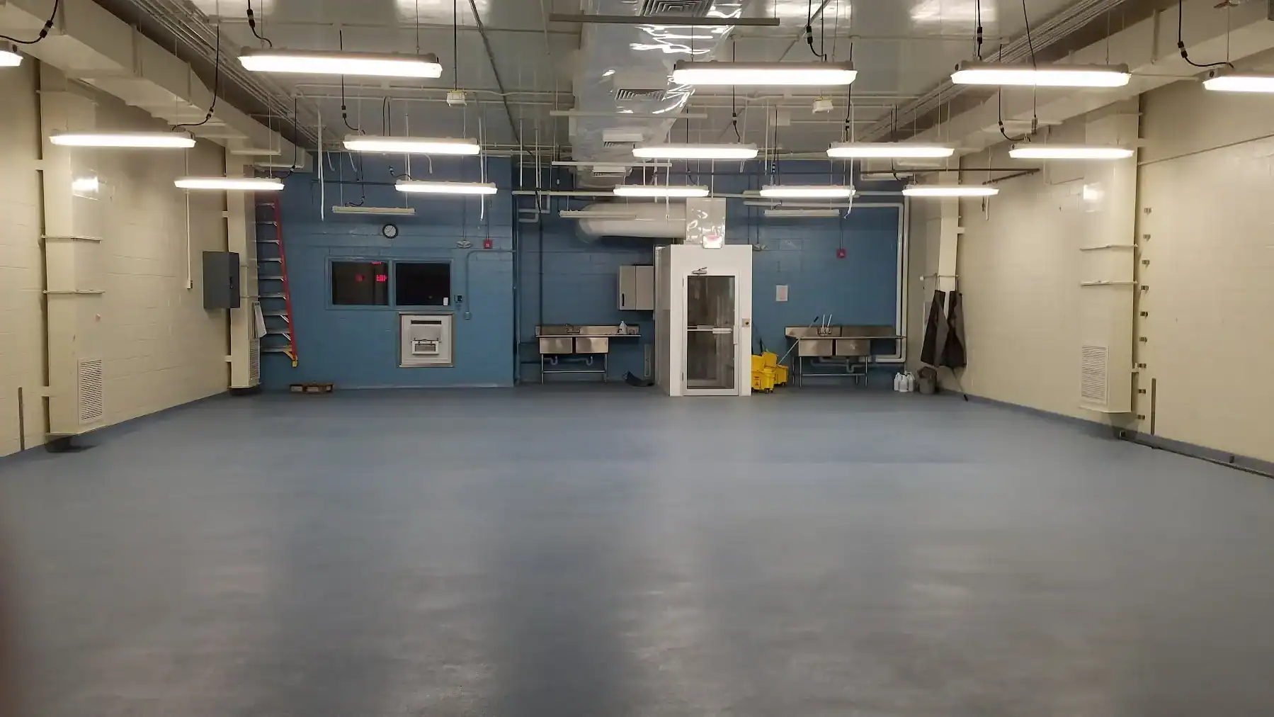 Gray Epoxy Garage Floor Coating Gray epoxy-coated commercial garage floor with seamless finish in industrial space with blue accent wall.