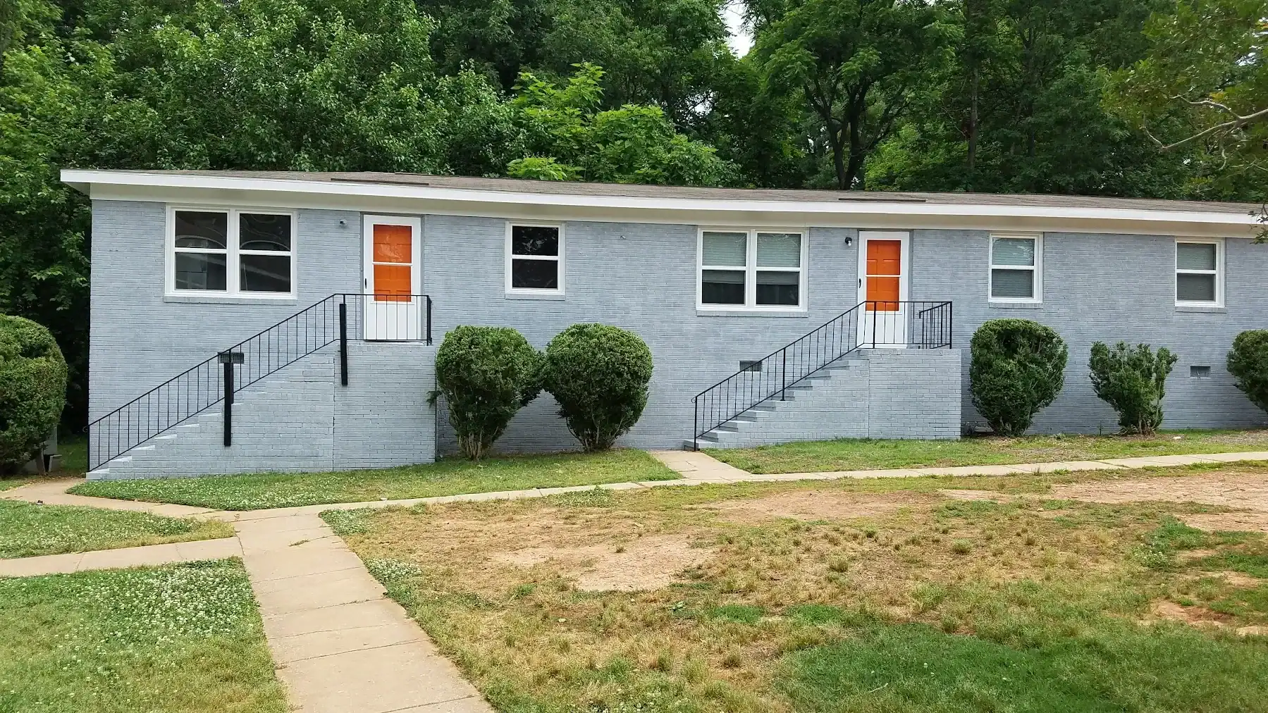 Light Blue Residential Building Exterior Light blue-painted multi-unit residential building with orange entry doors, black metal railings, and white-trimmed windows