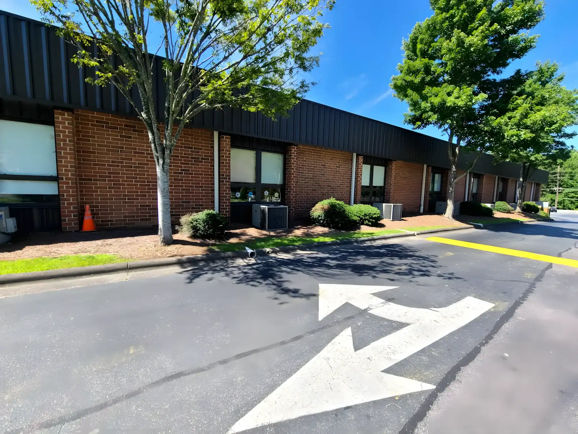Brick Commercial Building Exterior Red brick commercial building exterior with black metal roofing, white-trimmed windows, and painted parking lot striping.