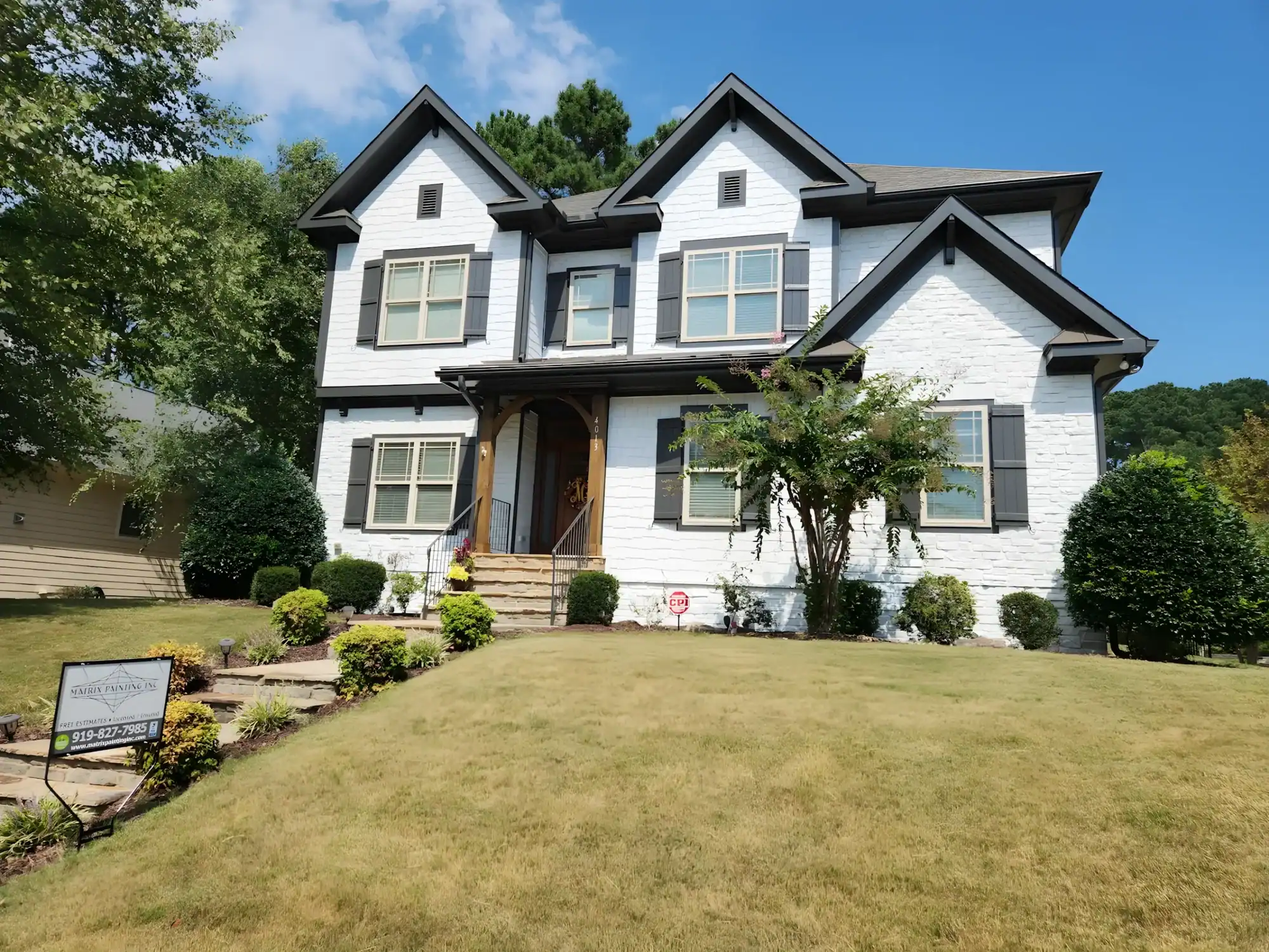 White-painted two-story residential home with black roof peaks, charcoal trim, and multi-pane windows in Raleigh, NC