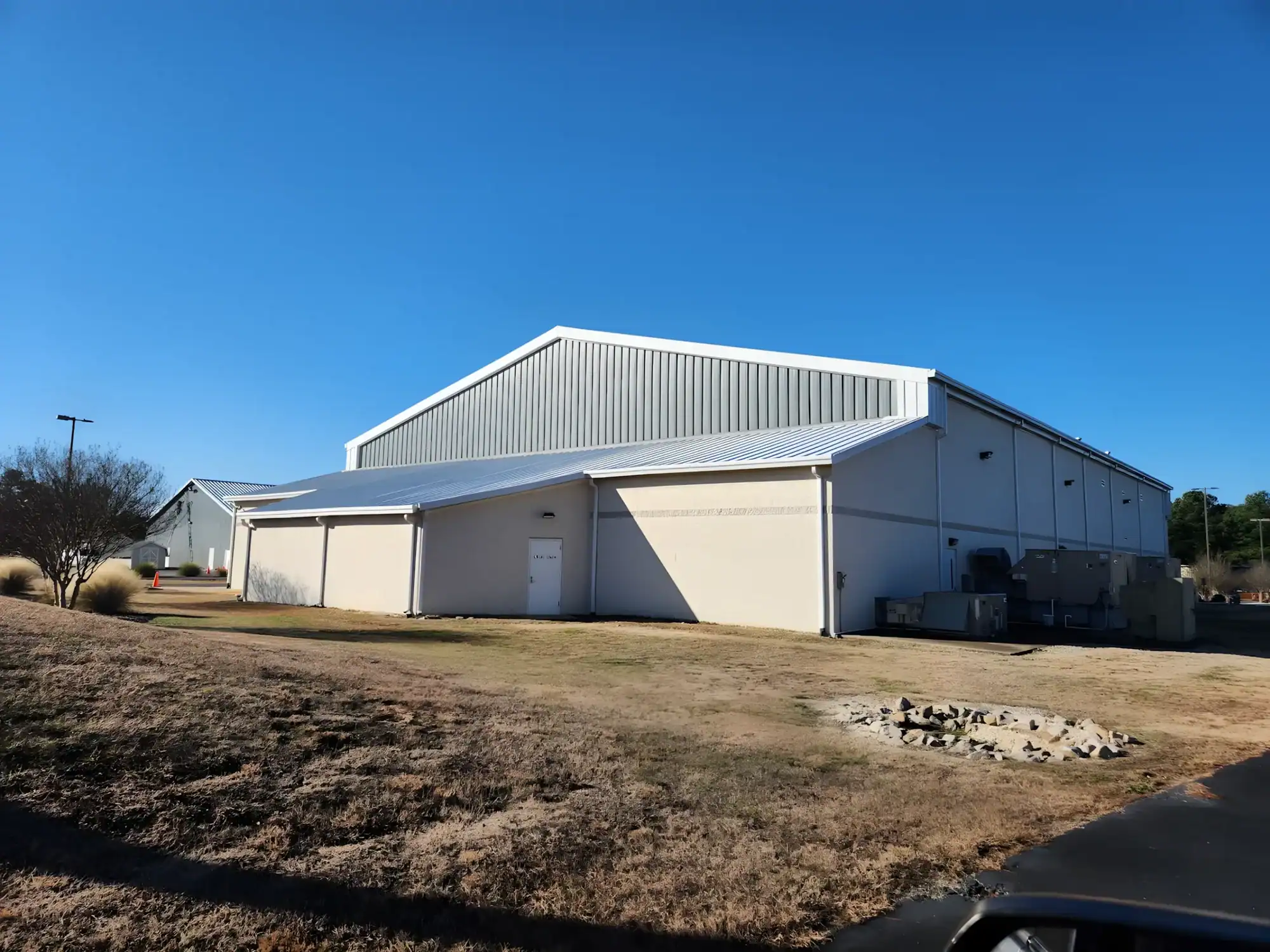 Cream Painted Agricultural Metal Building Cream-painted metal agricultural building with white trim, metal roof, and large garage doors in rural setting.
