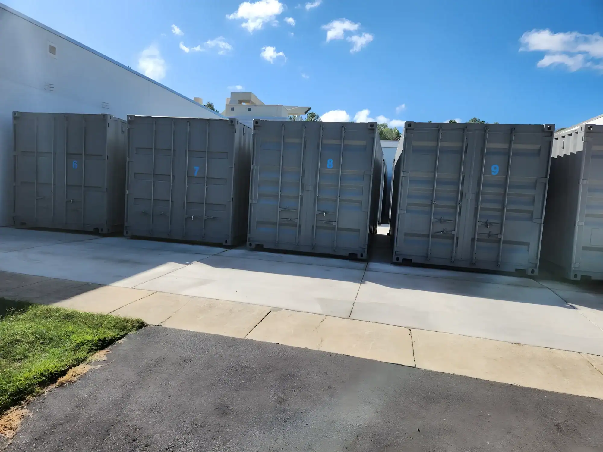 Gray Painted Storage Containers Gray-painted industrial storage containers with blue accent markings lined against concrete pad in commercial exterior