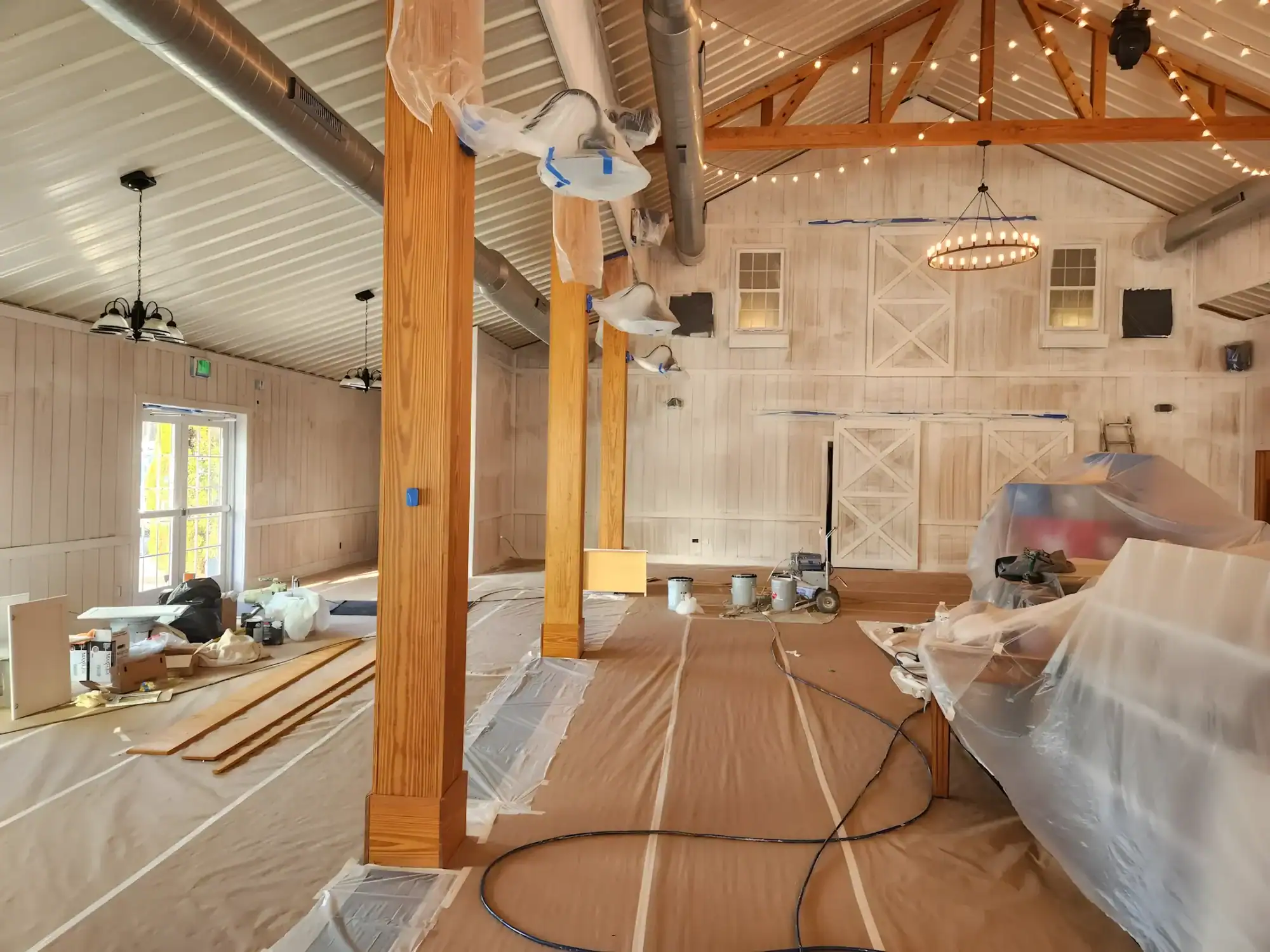 Tan Interior Barn Renovation Tan-painted commercial barn interior with exposed wood beams, protective coverings, and spray equipment during renovation