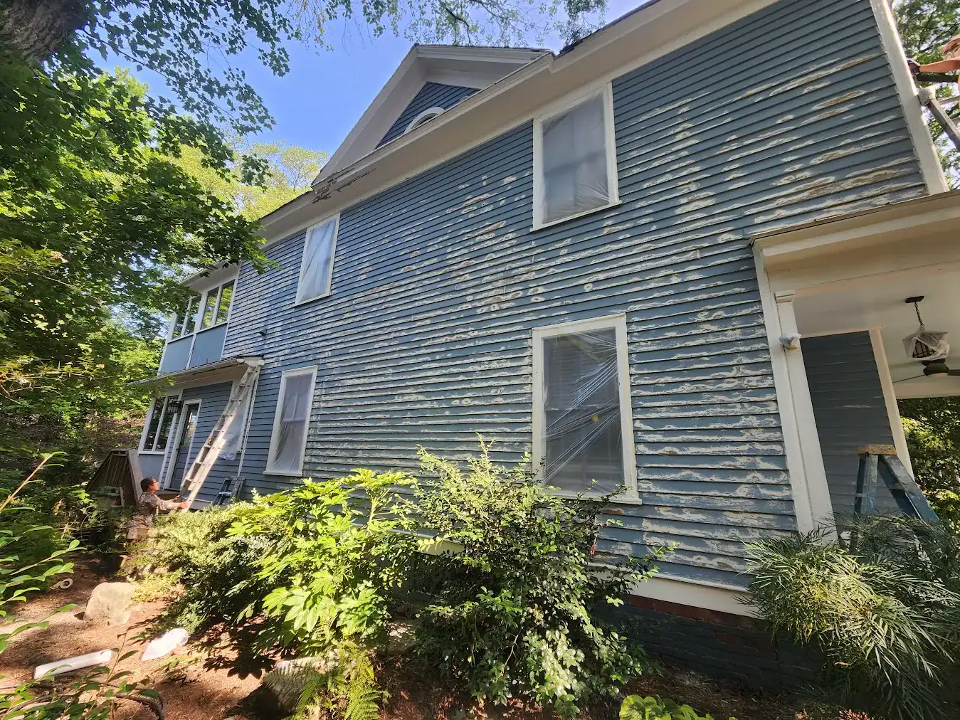 Blue horizontal-siding two-story residential home with white trim, multi-pane windows, and gable roof in Raleigh, NC