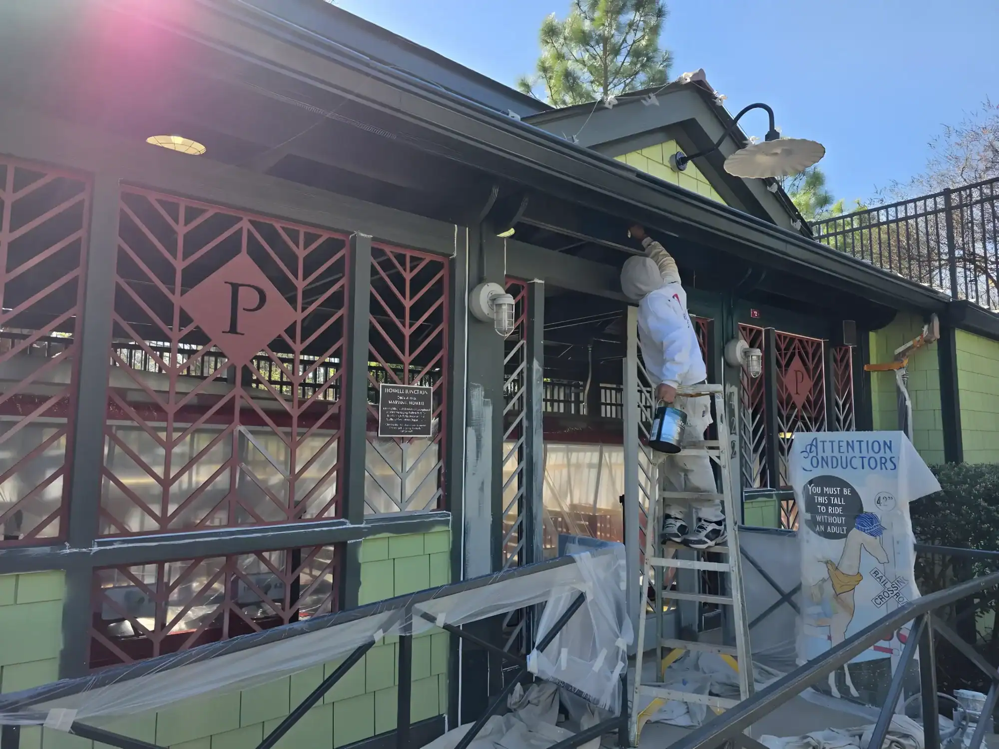 Residential Exterior Painting Project Light green-painted residential building exterior with dark gray trim and burgundy decorative gate panels during exterior