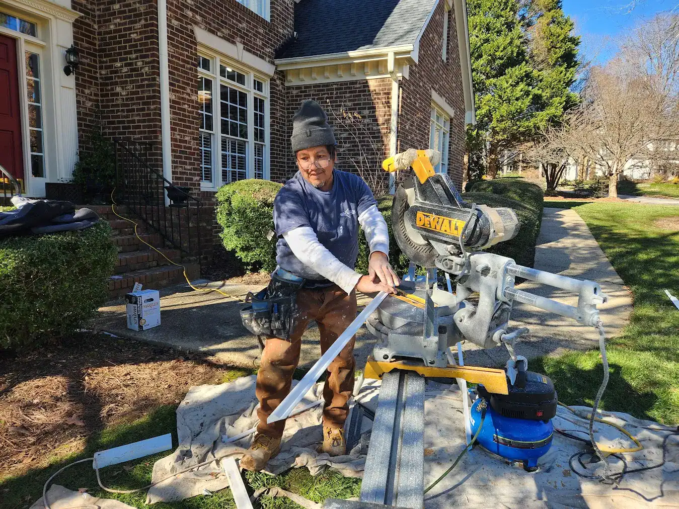 Exterior Trim Carpentry Work Contractor using power saw to cut trim for brick residential home exterior in Raleigh, NC